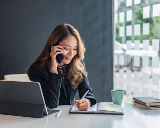 Woman-talking-on-mobile-phone-using-laptop