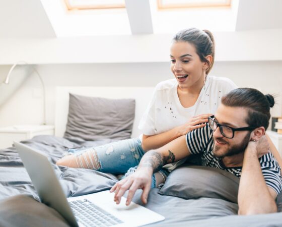 young man and woman watching movie on bed