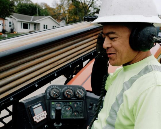 Telecommunications technician in hard hat sitting in piece of heavy equipment